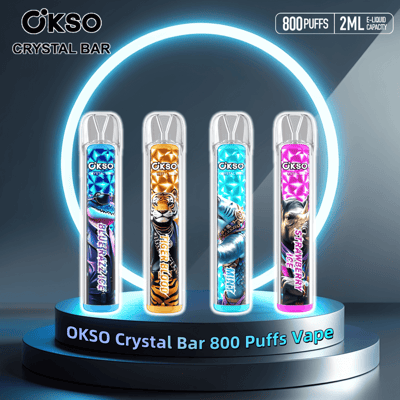 Four OKSO Crystal Bar vape pens with unique colorful designs and flavors, including Blue Razz Ice, Tiger Blood, Mint, and Strawberry Ice, displayed on a luminous platform with glowing accents; labeled with 800 puffs and 2ml e-liquid capacity.